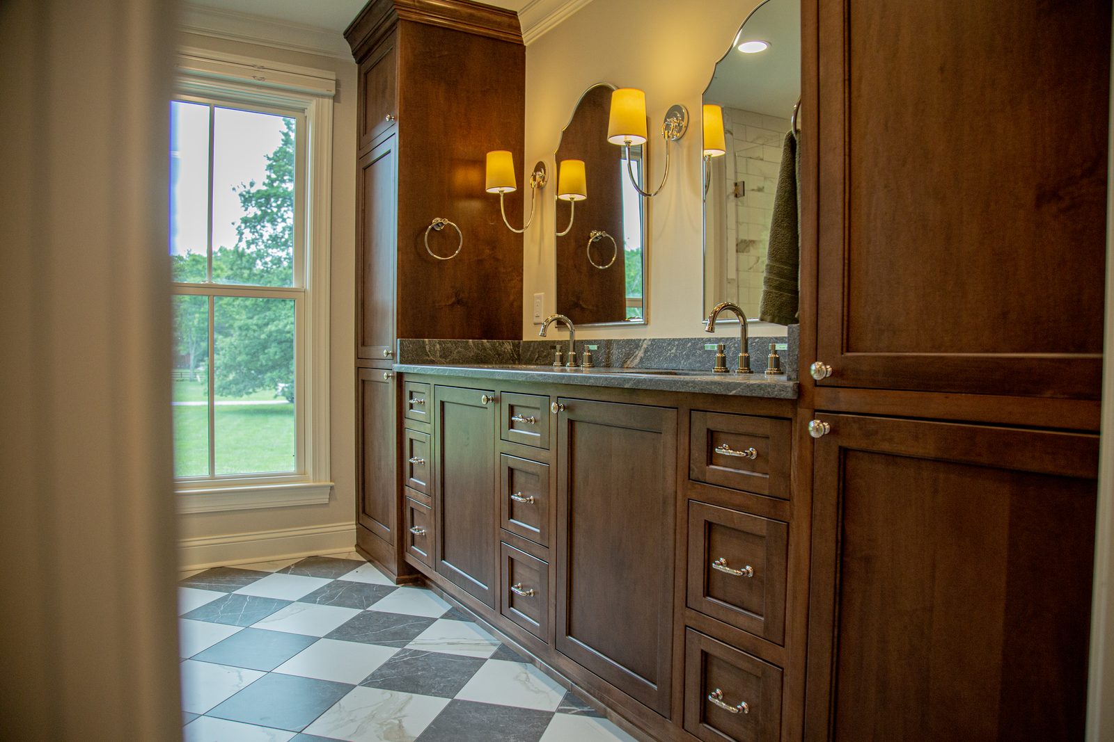 Custom bathroom with a stained wood vanity, marble counters, and a checkered marble floor
