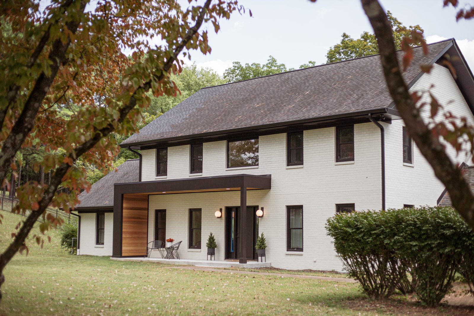 Modern farmhouse exterior with white siding and warm wood accents by Lionheart