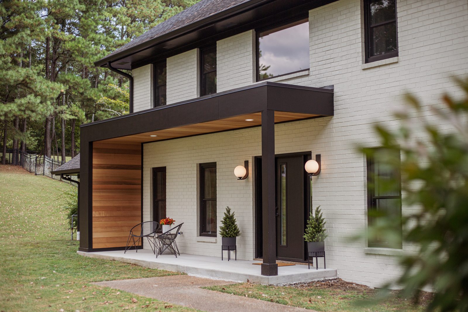 Painted brick home with a walnut-clad covered entry and black steel canopy