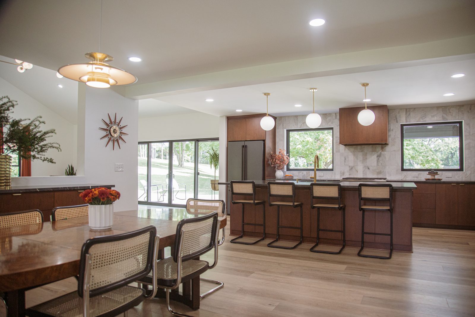 Mid-century modern kitchen and dining room with walnut cabinetry and globe pendants