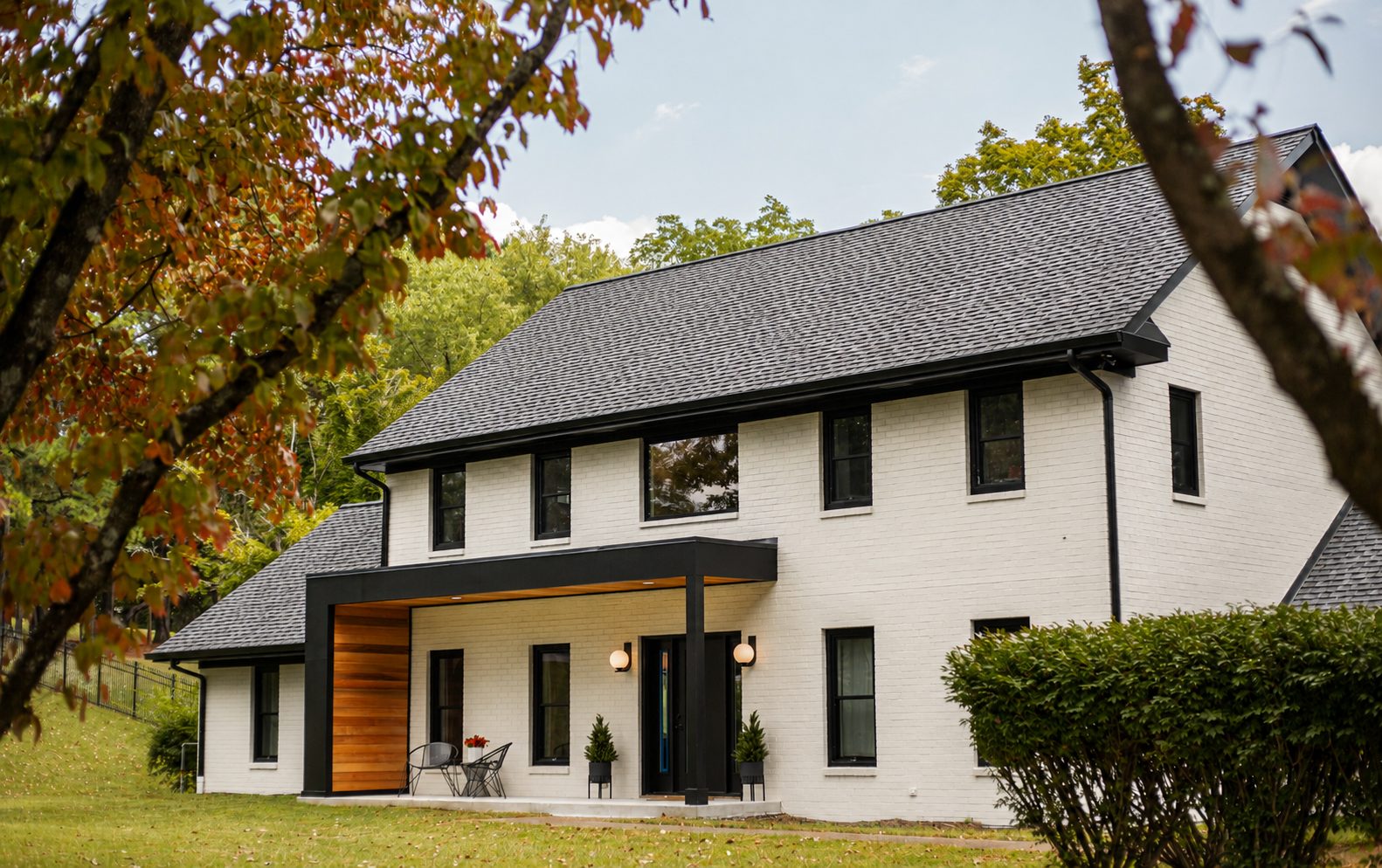 Whole-home renovation with painted brick, a dark standing-seam roofline, and a walnut entry canopy